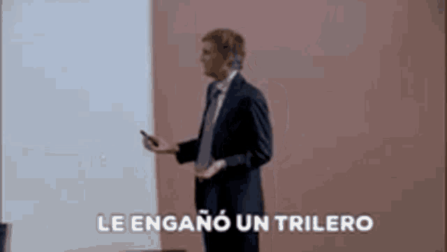 a man in a suit and tie is dancing in front of a wall with the words `` le engano un trilero '' .