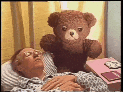 a man is laying in bed with a teddy bear