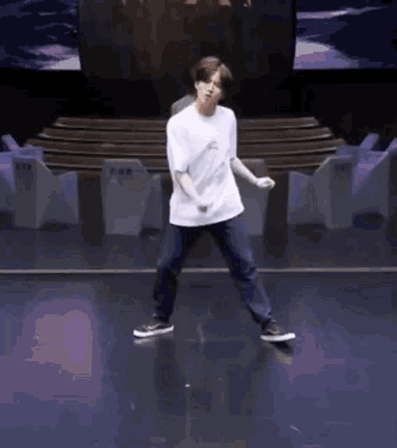 a young man is dancing on a stage in front of a crowd .