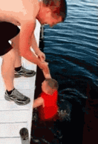 a man holds the hand of a baby who is in the water
