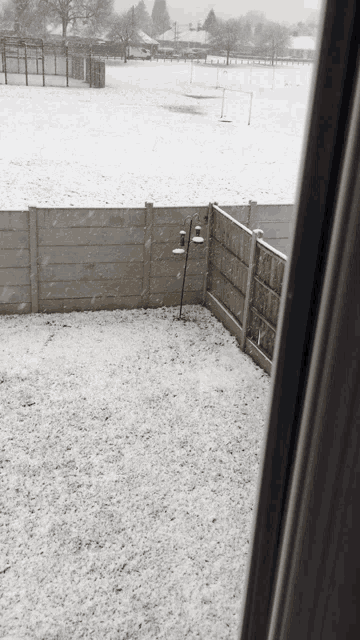a snowy yard with a fence and a lamp in the foreground