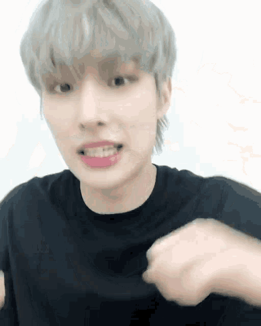 a young man with gray hair and pink lips is wearing a black shirt .