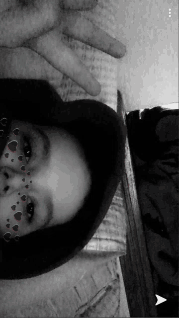 a black and white photo of a person wearing a hat and hearts on their face