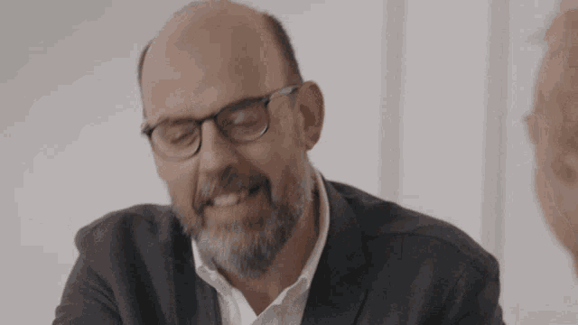 a man with glasses and a beard smiles for the camera