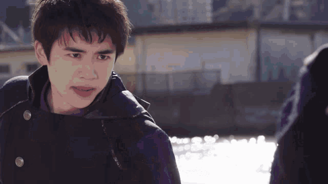 a young man wearing a black jacket and a purple shirt