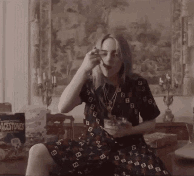 a woman in a dress is eating a bowl of cereal with a bag of black stones in the background