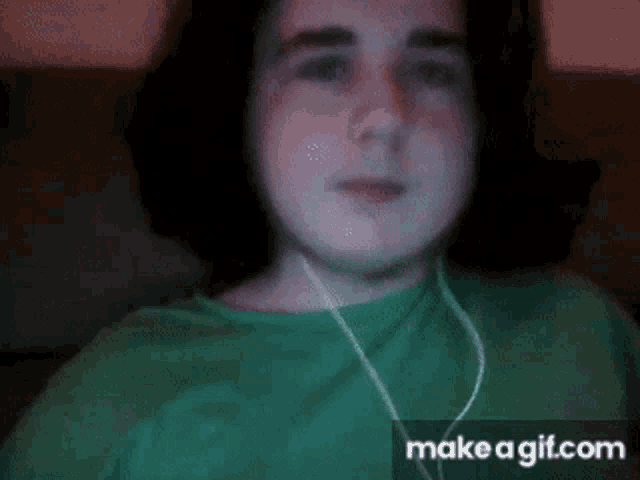 a young boy wearing headphones and a green shirt is sitting on a couch .