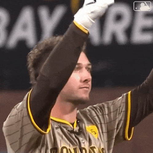 a man wearing a san diego padres jersey holds up his gloves