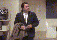 a man in a suit and tie is standing in a room holding a coat .