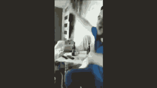 a man in a blue shirt is sitting at a table with his hand in the air .