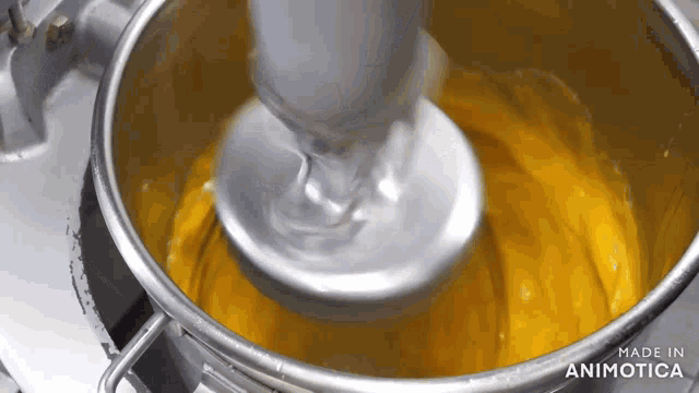 a mixer is being used to mix a yellow liquid and the words made in animotica can be seen in the background