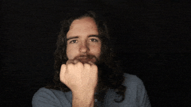 a man with long hair and a beard gives the middle finger