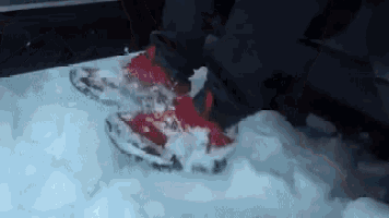a person wearing a pair of red snow shoes is standing in the snow .