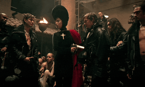 a woman with a cross on her chest is holding a gun in a crowd