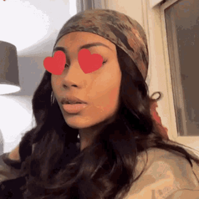 a woman wearing a head scarf and sunglasses with heart shaped eyes .
