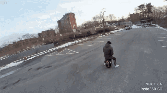 a person riding a scooter in a parking lot with insta360 go on the bottom