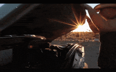 a man in a cowboy hat looks under the hood of a vehicle
