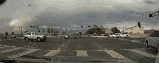cars are driving through an intersection with a red light in the background