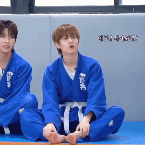a boy in a blue karate uniform is sitting on the floor