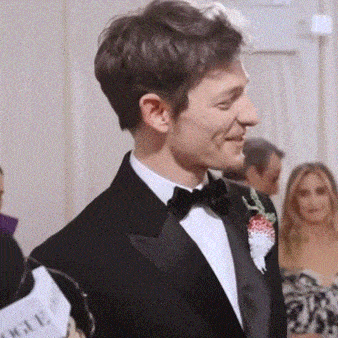 a man in a tuxedo has a sign that says vogue in front of him