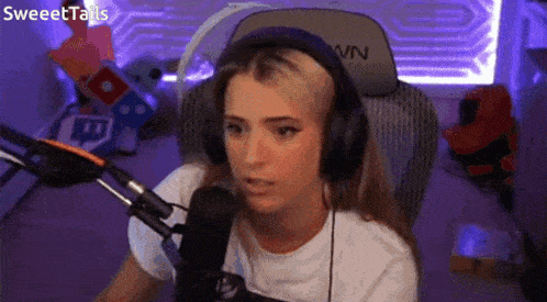 a woman wearing headphones and a white shirt is sitting in front of a microphone in a purple room .
