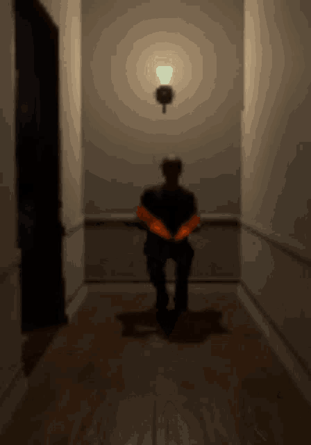 a man is sitting in a dark hallway with a light on