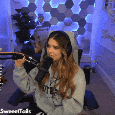 a woman wearing headphones is sitting in front of a microphone with the words sweettails on the bottom