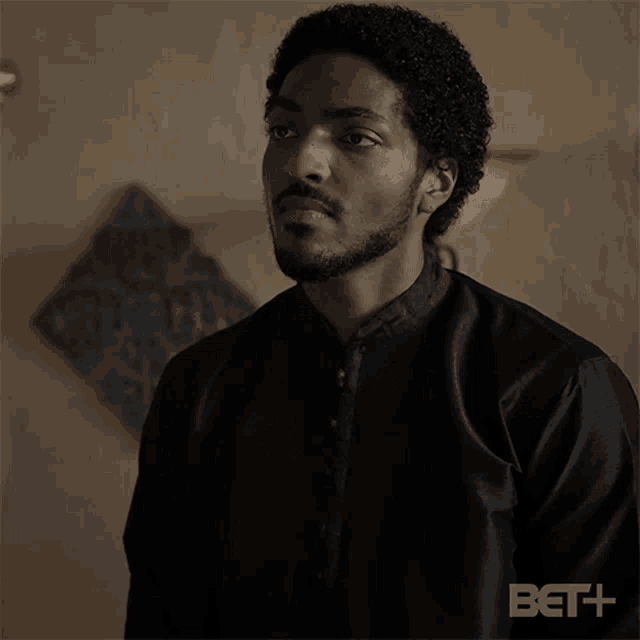 a man with a beard wearing a black shirt is standing in a room .