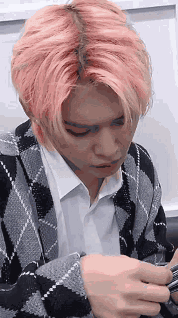 a man with pink hair is wearing a plaid jacket and a white shirt .