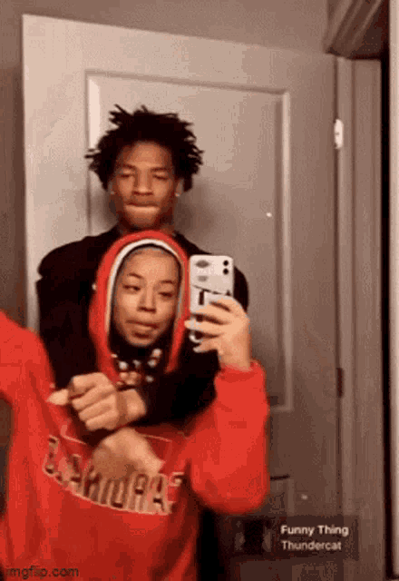 a girl in a red hoodie is taking a picture of herself with her phone