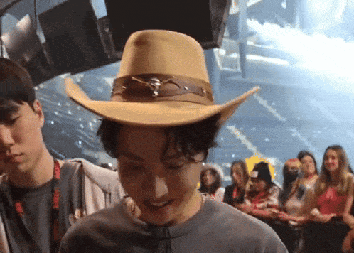 a man wearing a cowboy hat stands in front of a crowd of people