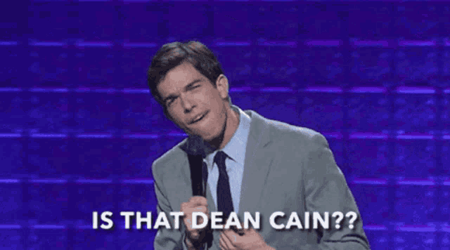 a man in a suit and tie stands in front of a microphone and says is that dean cain