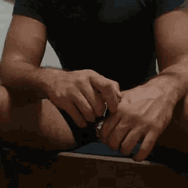a man in a black shirt is sitting on a chair holding a key .