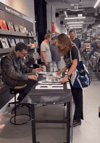 a man sits at a table with a sign that says rough trade books