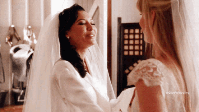 a woman in a wedding dress is standing next to another woman in a robe