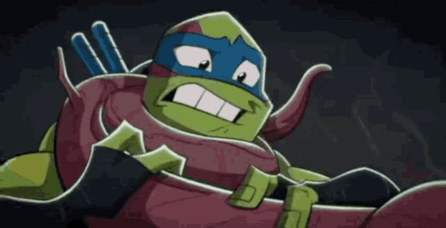a teenage mutant ninja turtle is making a funny face while holding something in his hands .