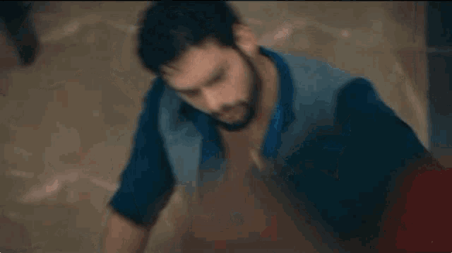 a man with a beard and a watch is pointing at the camera .