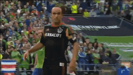 a man in a herbalife jersey stands on a soccer field