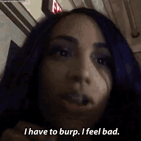 a woman with purple hair is talking to the camera and saying `` i have to burp . i feel bad . ''