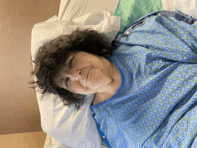 an elderly woman in a hospital gown is laying on a bed