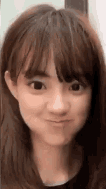 a close up of a woman 's face with bangs making a face .