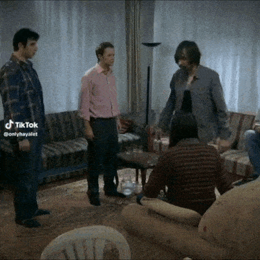a group of men are standing in a living room with tiktok written on the bottom right