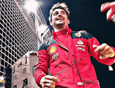 a man in a red and black jacket is standing in front of a building and smiling .