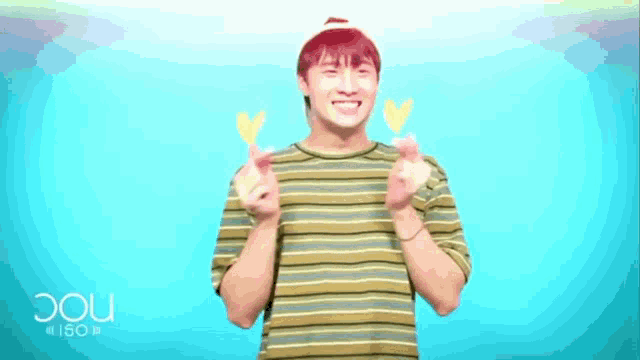 a young man wearing a striped shirt is making a heart with his hands