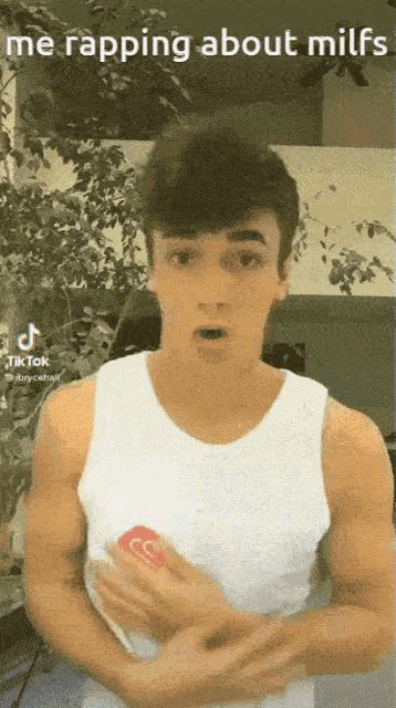 a man in a white tank top is holding a can of coca cola