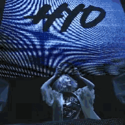 a man stands in front of a large screen with the word ayo on it