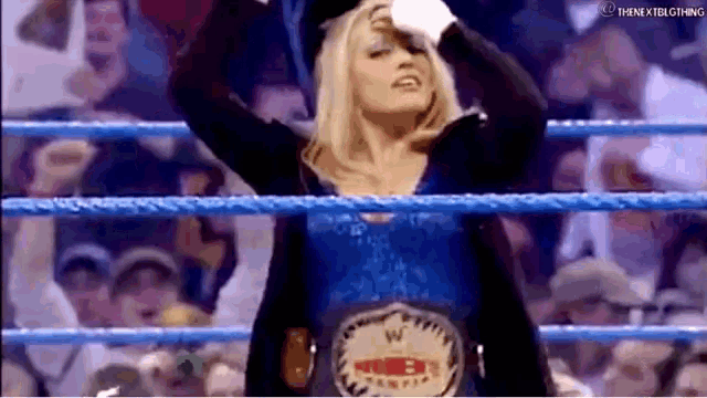a woman is standing in a wrestling ring wearing a world heavyweight wrestling belt .