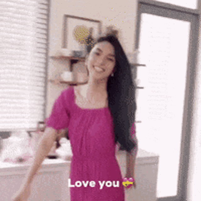 a woman in a pink dress is dancing with the words love you behind her