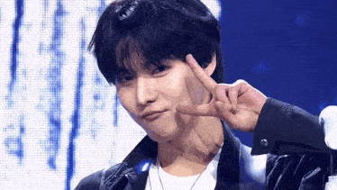 a young man is making a peace sign with his hands