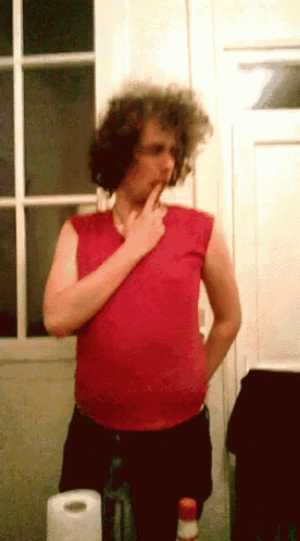 a man with curly hair is standing in front of a toilet paper roll